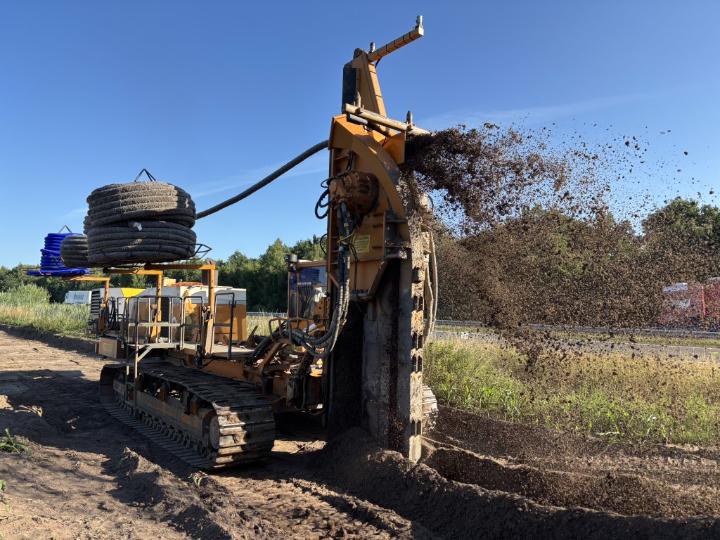 Diepe bouwput in woonwijk met actieve bronbemaling, graafmachines en pompen voor verlaging van het grondwaterpeil tijdens bouwwerkzaamheden.