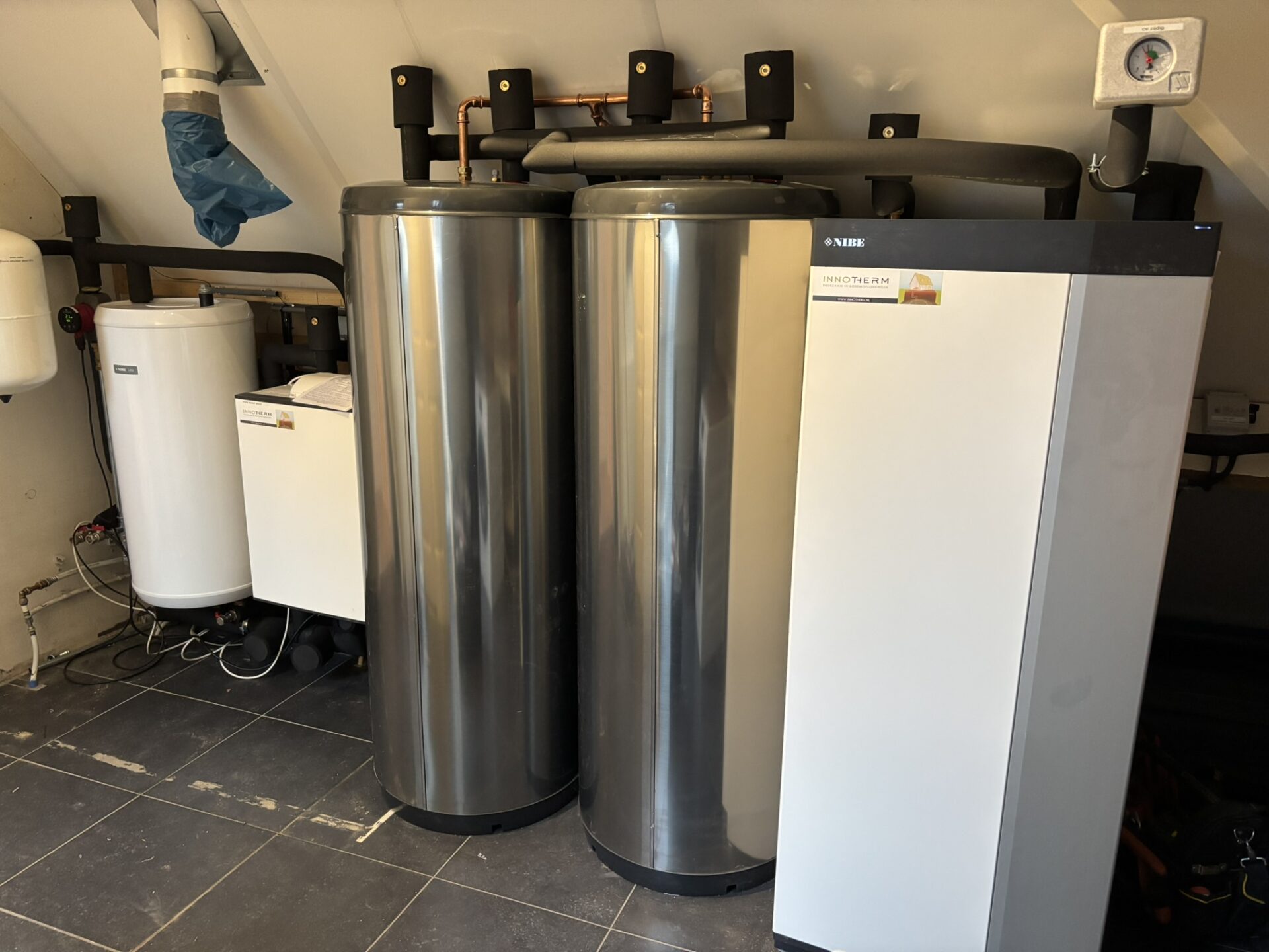 Warmtepompinstallatie van InnoTherm met twee opslagtanks en leidingen in een technische ruimte.